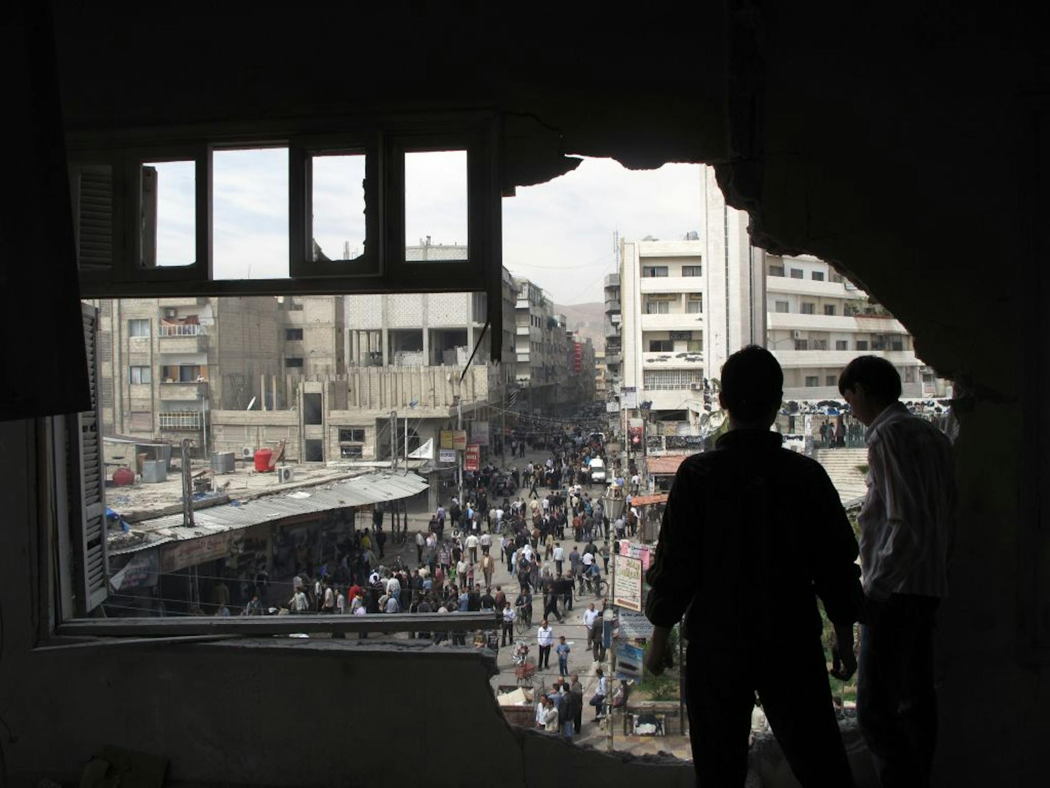 Syrian youth stand in a building damaged by tank shells in a neighborhood of Damascus.