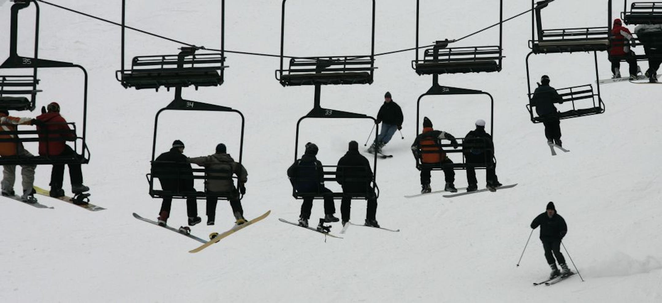 Skis and snow boards dangle above a skier who enjoys one of the steeper hills at Afton Alps.