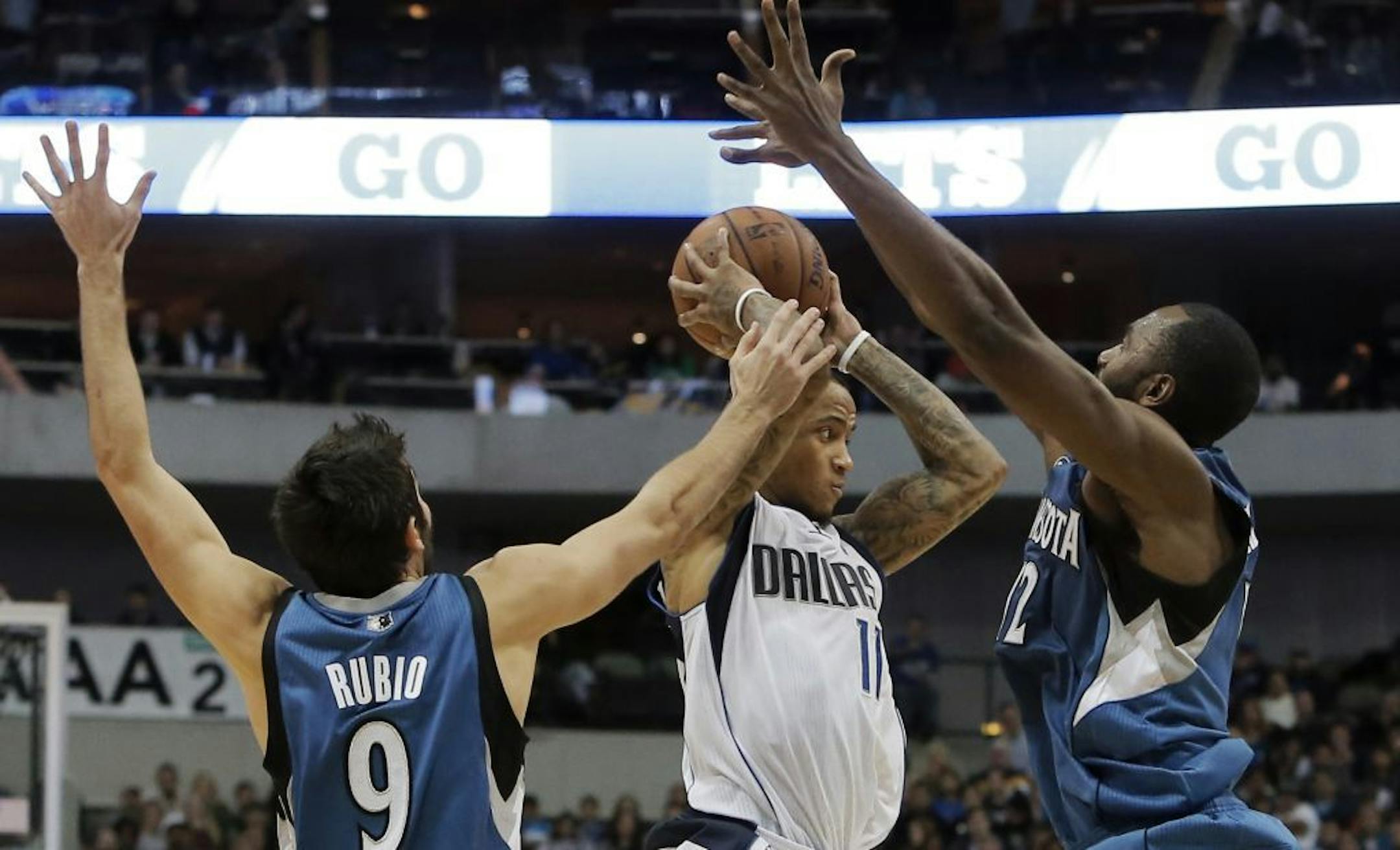 Dallas Mavericks guard Monta Ellis (11) looks for an open teammate as Minnesota Timberwolves Ricky Rubio (9) and Luc Richard Mbah a Moute (12) defend during the second half of an NBA basketball game Saturday, Nov. 30, 2013, in Dallas. Minnesota won 112-106.