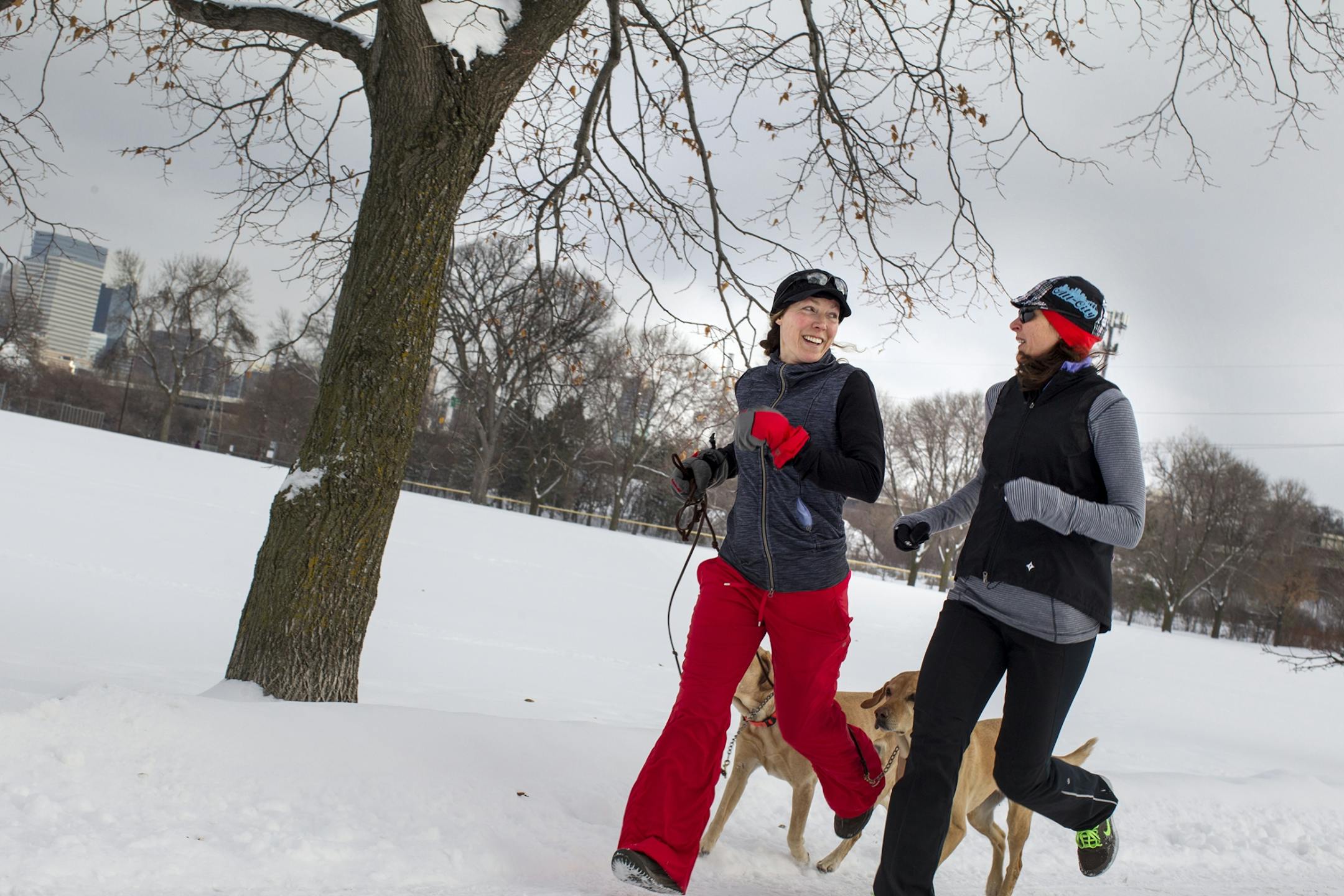 Amber Schult, right, runs with Liz McLay and her dogs, Pooperton and Daisy, through Bryn Mawr Meadows in Minneapolis Dec. 25, 2013.