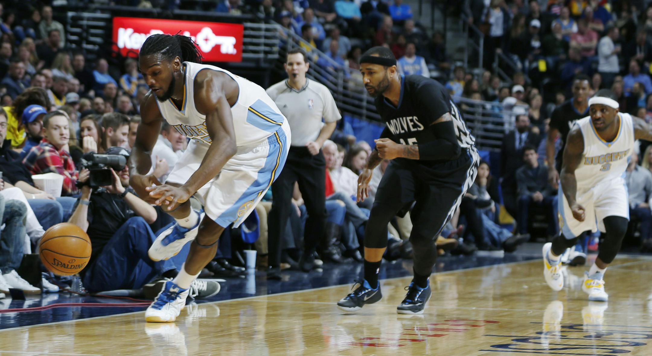 Denver Nuggets forward Kenneth Faried, left, picks up a loose ball as Minnesota Timberwolves guard Mo Williams, center, and Nuggets guard Ty Lawson watch during the third quarter of an NBA basketball game Saturday, Jan. 17, 2015, in Denver. The Timberwolves won 113-105. (AP Photo/David Zalubowski)