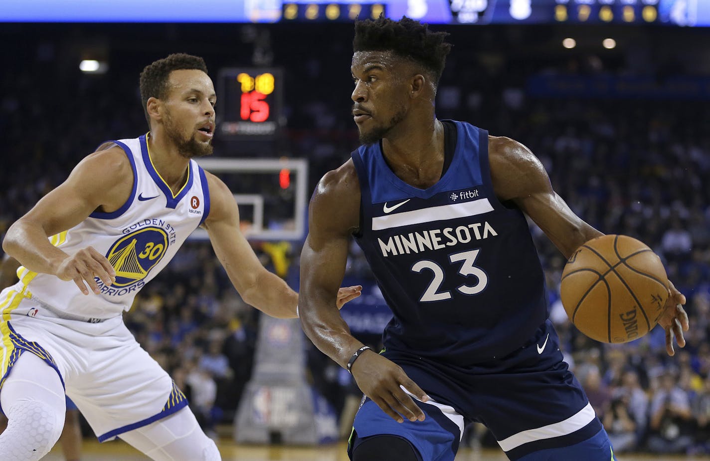 Minnesota Timberwolves' Jimmy Butler, right, drives the ball against Golden State Warriors' Stephen Curry (30) during the first half of an NBA basketball game Wednesday, Nov. 8, 2017, in Oakland, Calif. (AP Photo/Ben Margot)