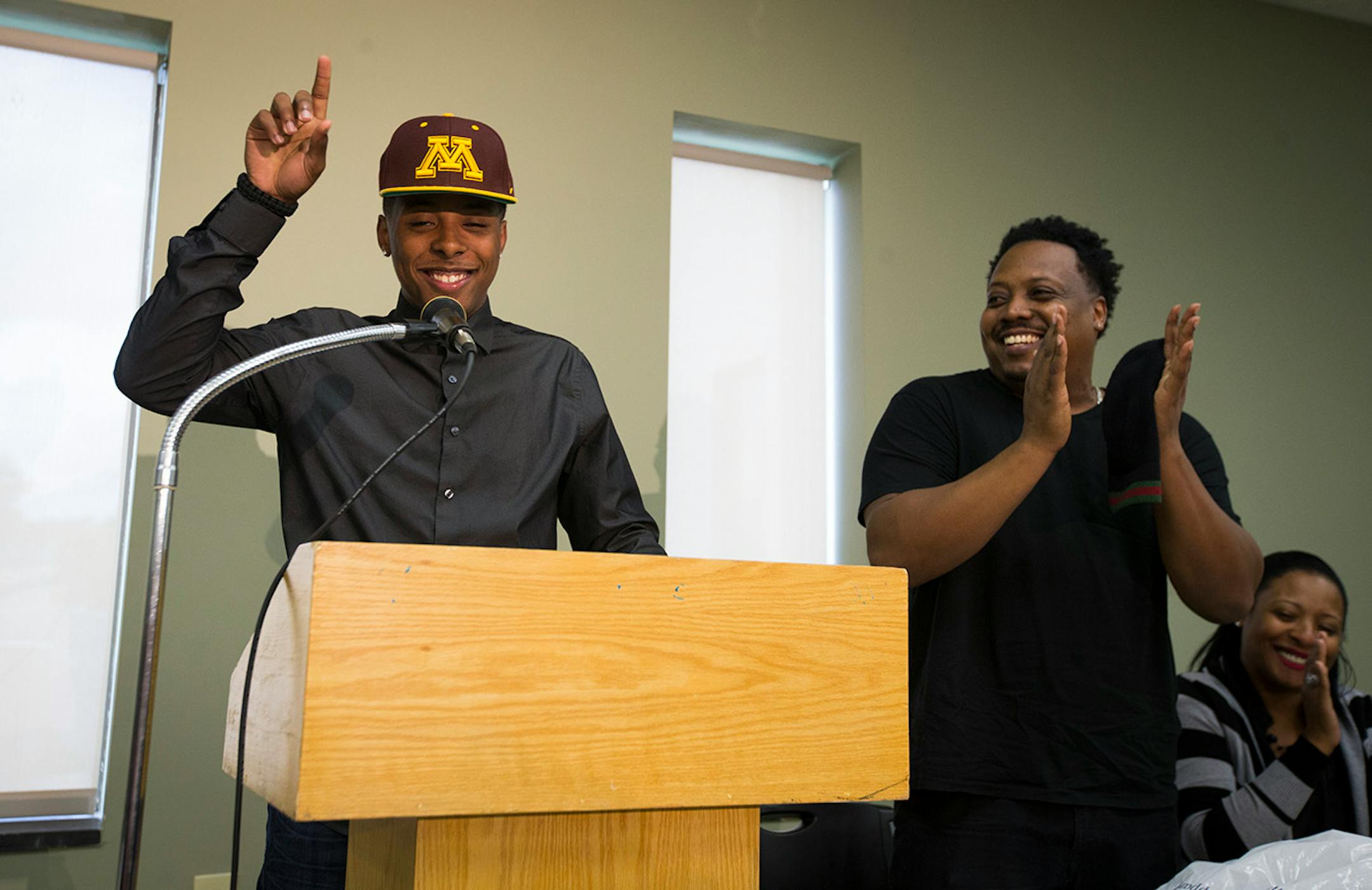 Jarvis Johnson, DeLaSalle basketball star, put on a Gopher's hat as announced his college choice of the University of Minnesota at DeLaSalle High School on Friday, Sept. 12, 2014, in Minneapolis, Minn. At right is his father Curtis Johnson. ] RENEE JONES SCHNEIDER • reneejones@startribune.com