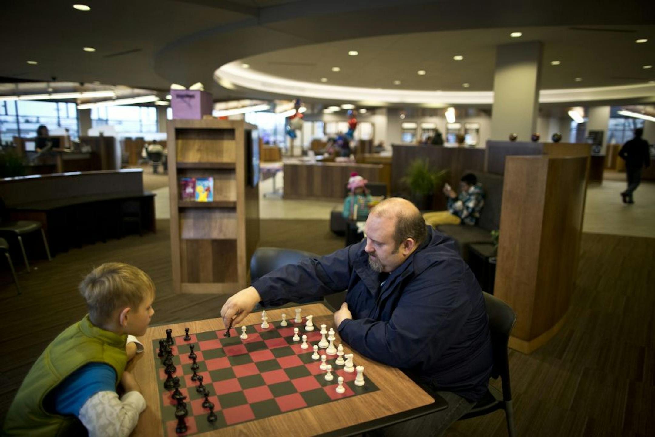 Shane Lourey of Mounds View taught his son Brady, 9, how to play chess as he waited for his new debit card to be made at Affinity Plus Fed Credit Union in Roseville, Minn., on Friday, November 9, 2012. Lourey, who works at a competitive bank, prefers banking at the credit union because of the higher interest rates.