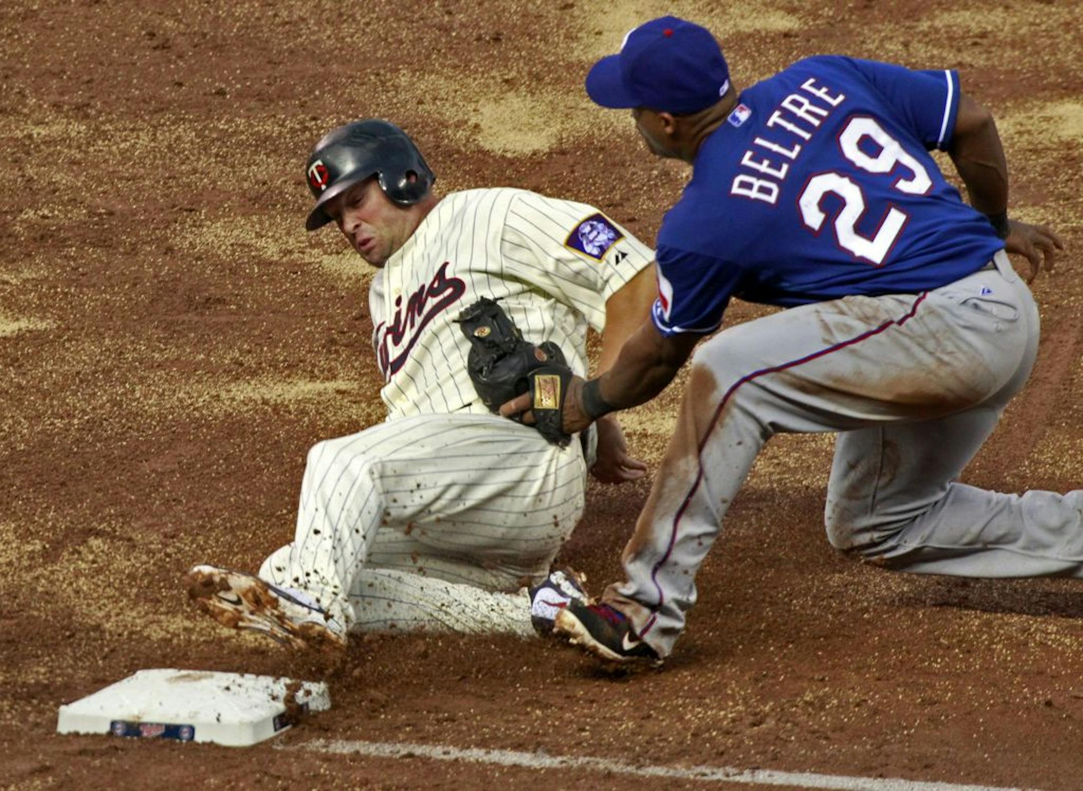 Minnesota Twins baserunner Michael Cuddyer, left, gets tagged out on a tag-up play by Texas Rangers third baseman Adrian Beltre in the third inning at Target Field in Minneapolis, Minnesota, Friday, June 10, 2011.