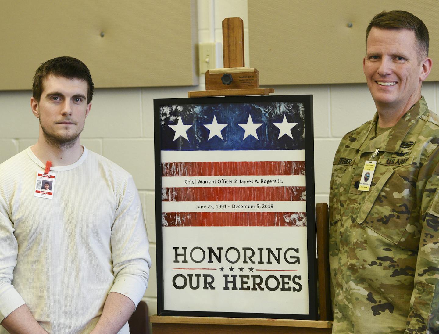 Jason Ricci and Jeremy Degeier pose for a photo with the painting honoring Chief Warrant Officer 2 James A. Rogers Jr. Wednesday, Mar. 4, 2020, at the St. Cloud prison.