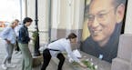 People place flowers and light candles in front of a picture of Liu Xiaobo, placed outside the Nobel's Peace center in Oslo, Thursday, July 13, 2017. 