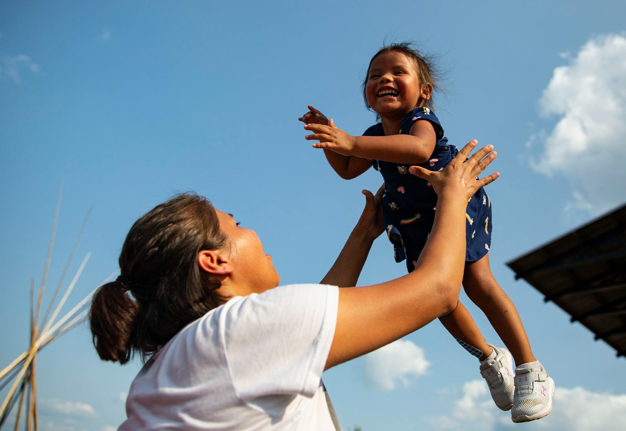 Sara Decorah tossed her daughter, Jona Edwards, 3, in the air as they listened to Charlie Parr perform at the Water is Life Festival on Wednesday.