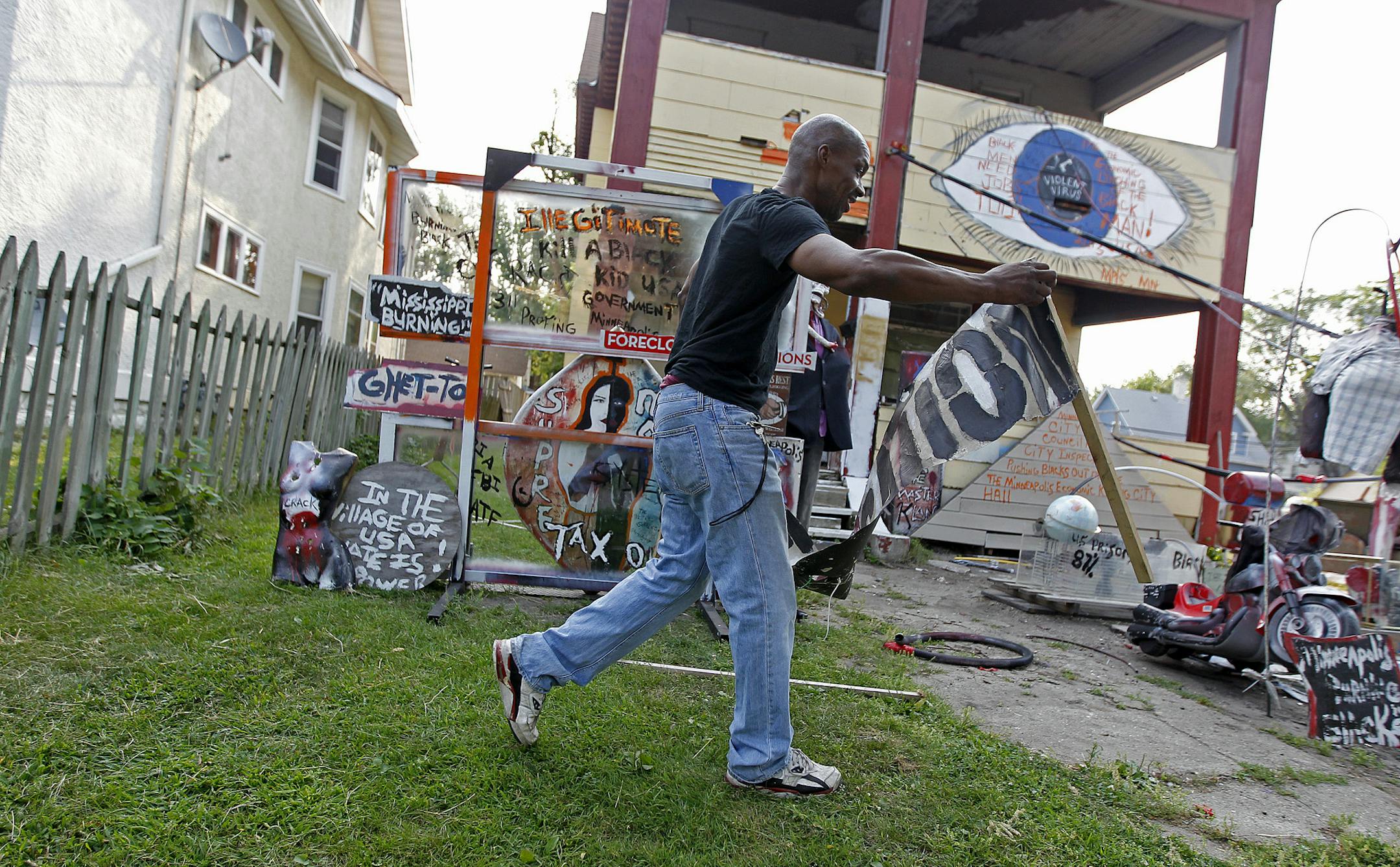Andrew Moore sifted through pieces of art that he has to rid of, Wednesday, August 21, 2013 in Minneapolis, MN. Powderhorn Park lawn artist, enemy of City Hall and homeowner Andrew Moore may get thrown out of his house at 3255 Bloomington Ave. S. as city officials move to condemn the property. He's long fought with city officials over his front yard art display, a collection of political signs, things pulled from the trash and other odds and ends, but mostly odds. (ELIZABETH FLORES/STAR TRIBUNE)