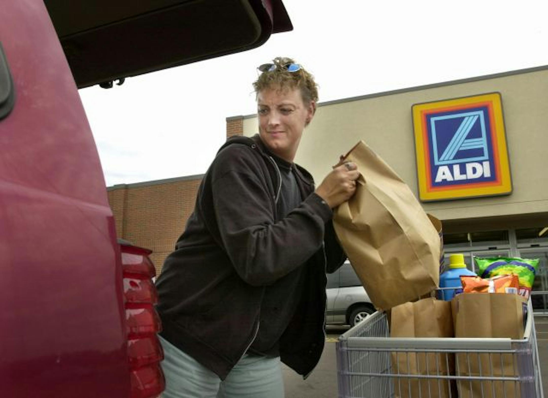 Menomonie, WI, Tuesday, July 22, 2003 -- Lisa McIntyre of Boyceville, Wisconsin, loads her cart of groceries, purchased at Aldi, into her minivan. Aldi, the no-frills German grocer is taking on the Twin Cities this fall with its unusual bare-bones strategy. But other concepts by Supervalu and Nash Finch have also entered the fray.