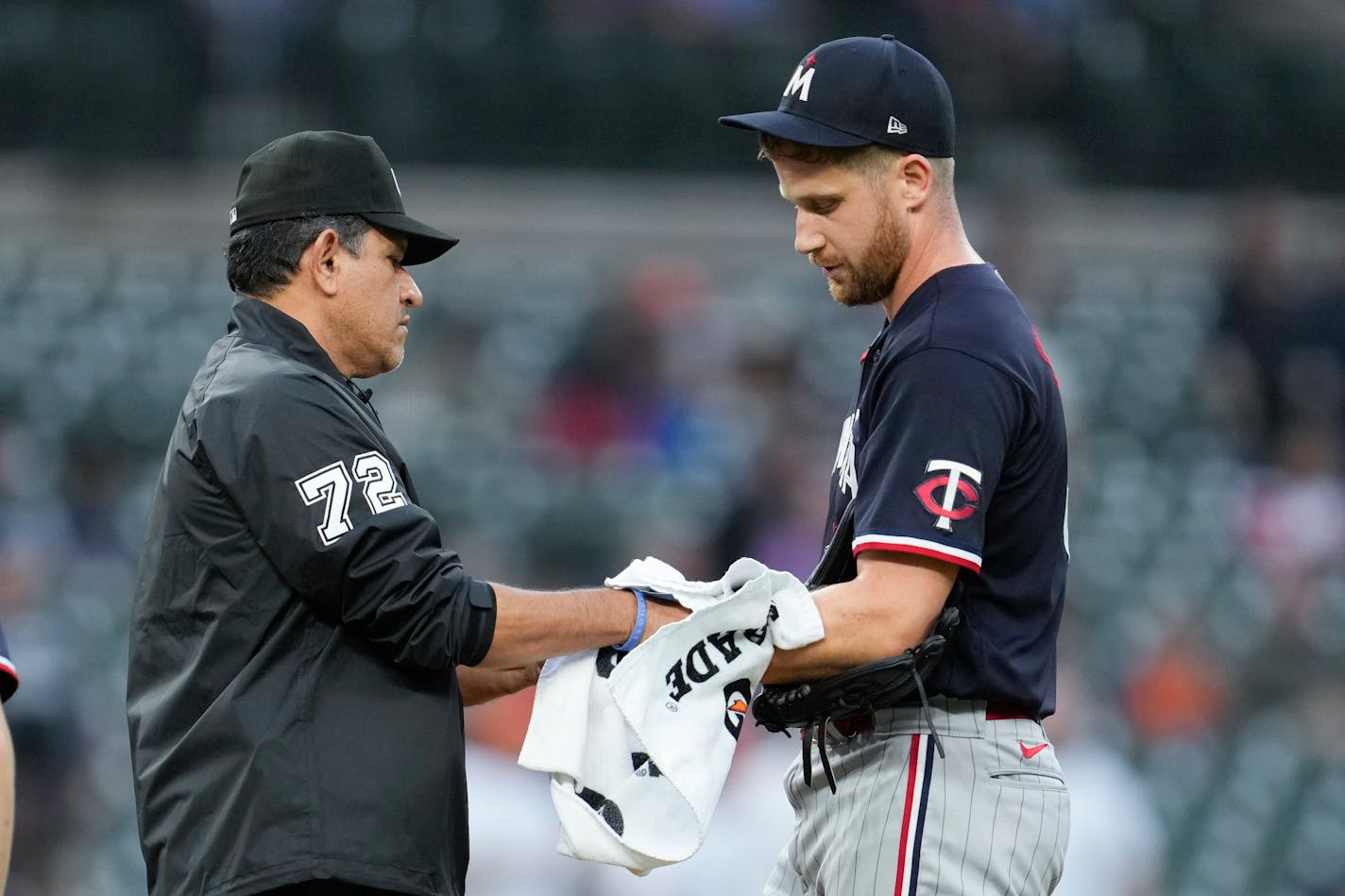 Umpire Alfonso Marquez wipes the arm of Minnesota Twins relief pitcher Brock Stewart with a towel in the sixth inning of a baseball game against the Detroit Tigers, Friday, June 23, 2023, in Detroit. (AP Photo/Paul Sancya)