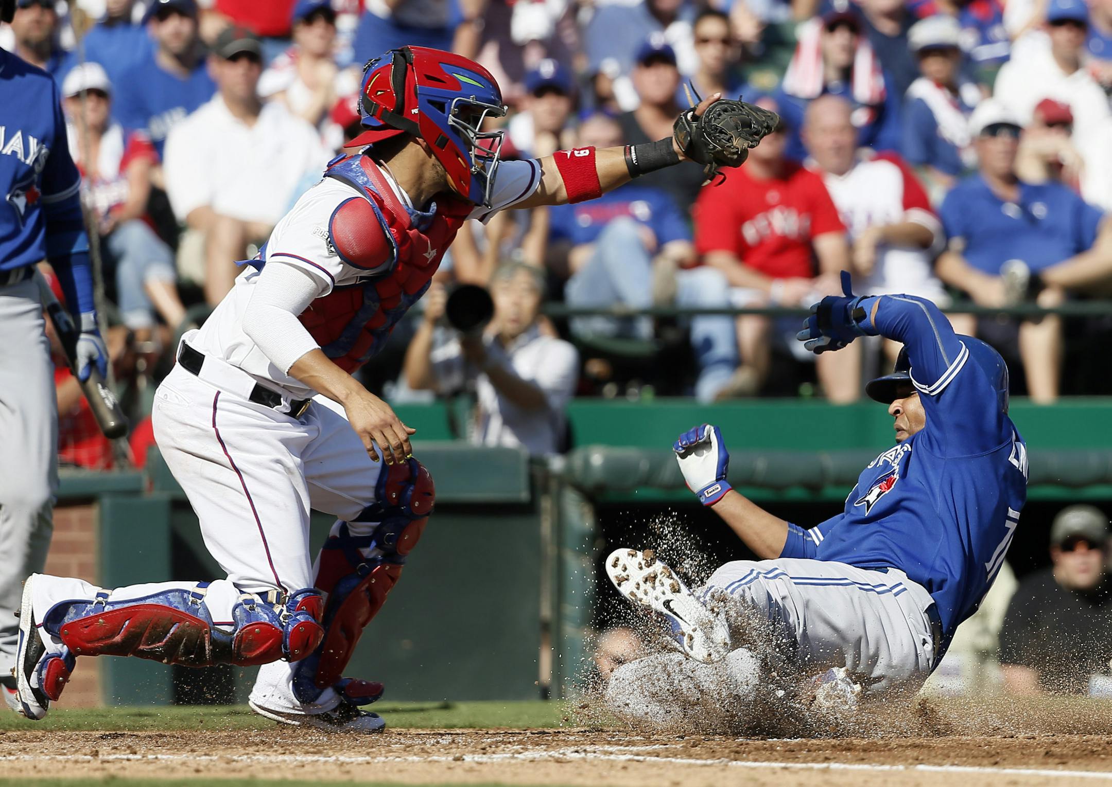 Toronto Blue Jays designated hitter Edwin Encarnacion (10) scores under Texas Rangers catcher Robinson Chirinos (61) during the third inning in Game 4 of baseball's American League Division Series Monday, Oct. 12, 2015, in Arlington, Texas. (AP Photo/Tony Gutierrez)