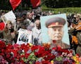 Communists stand with a portrait of Soviet dictator Josef Stalin during a ceremony to mark 70th anniversary of the end of WWII in front of the Memoria