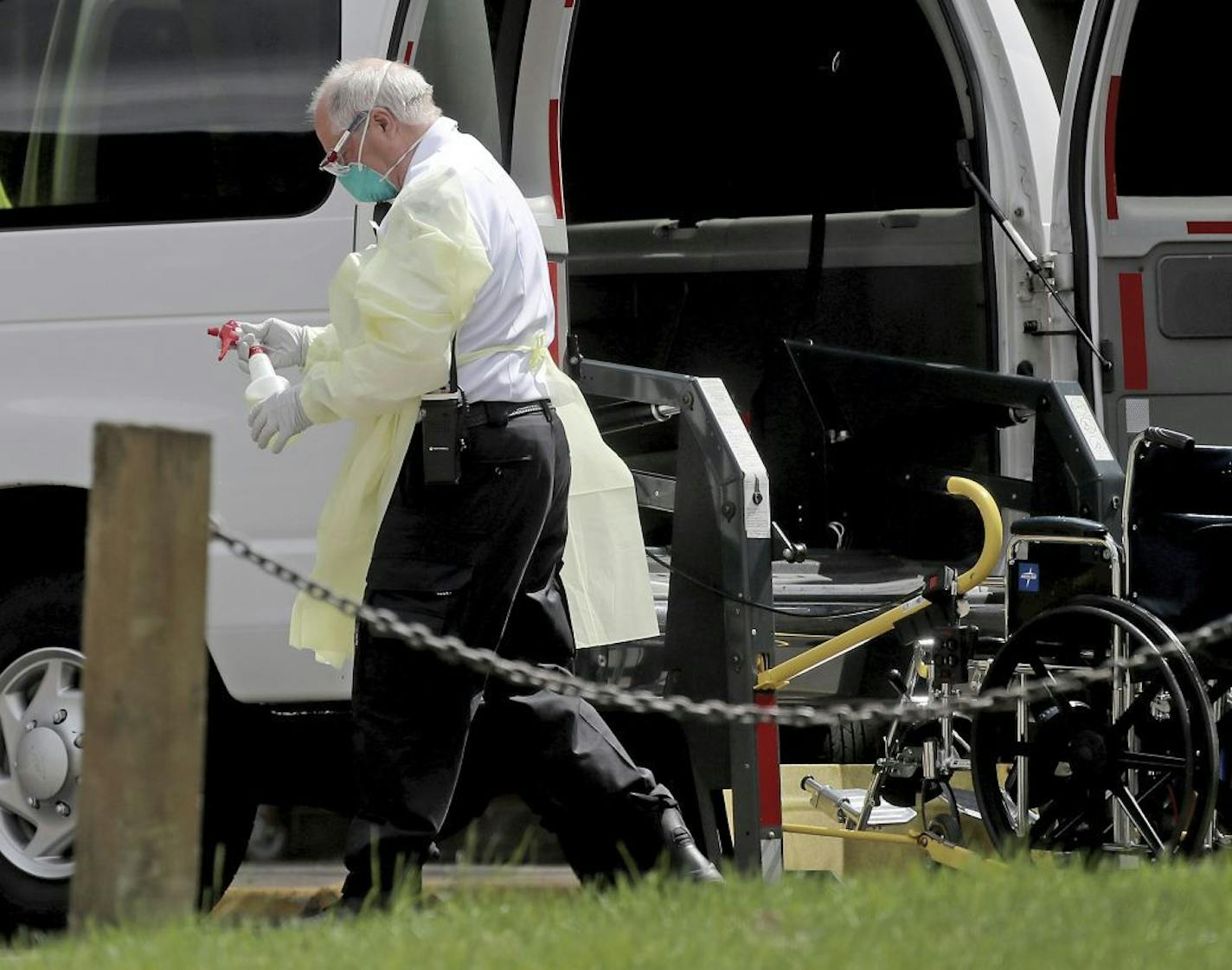 A North Memorial transport worker held a bottle of disinfectant Wednesday outside North Ridge Health and Rehabilitation, where multiple residents have died and become infected in New Hope.