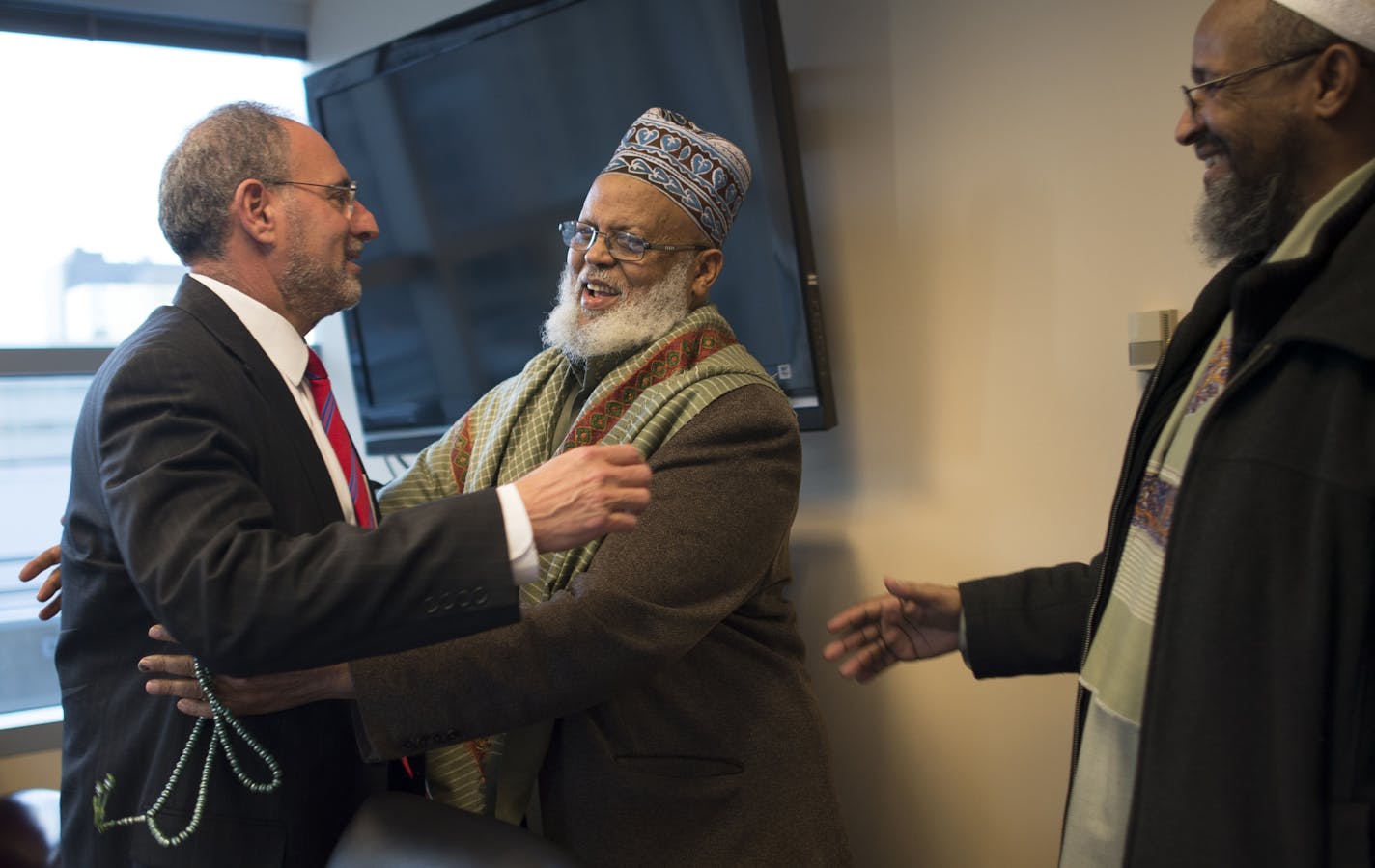 Imam Sheikh Sa'ad Musse Roble, with the World Peace Organization, hugs U.S. Attorney Andy Luger alongside Imam Ahmed Burale before Wednesday night's Somali community meeting at the U.S. Attorney's office. ] (Aaron Lavinsky | StarTribune) Members of the Minnesota Somali Muslim community meet with U.S. Attorney Andy Luger in his office on Wednesday, Feb. 11, 2015 in downtown Minneapolis. Luger is leading a Muslim outreach initiative in hopes of thawing relations and thwarting terrorist groups from