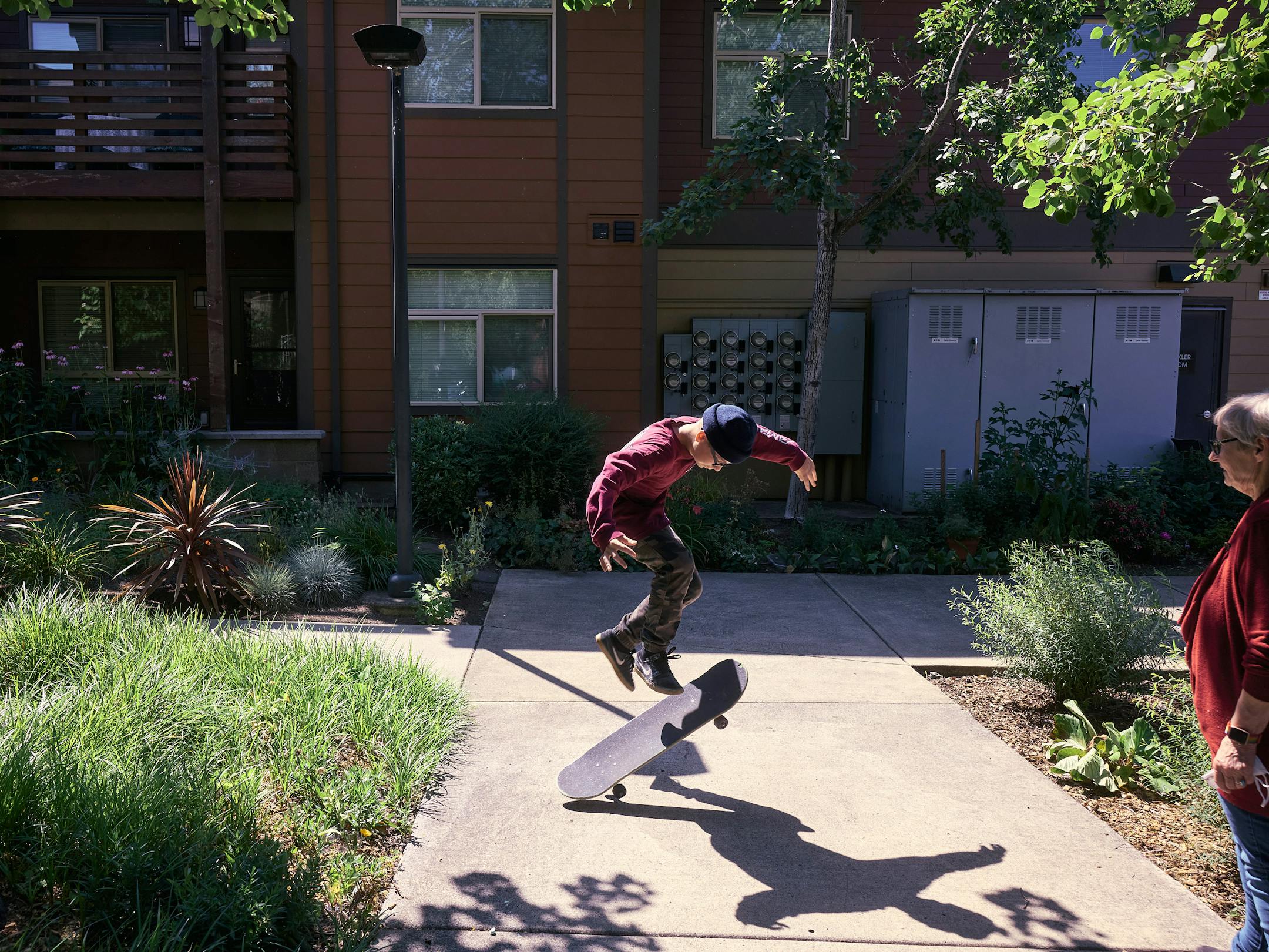 Jackie Lynn, right, looks on as her son Brodie practices skateboarding as they take a break from moving out of their home at Bridge Meadows Apartments in Portland, Ore., on July 12, 2021. Lynn and her family had lived there for a decade. (Mason Trinca/The New York Times)