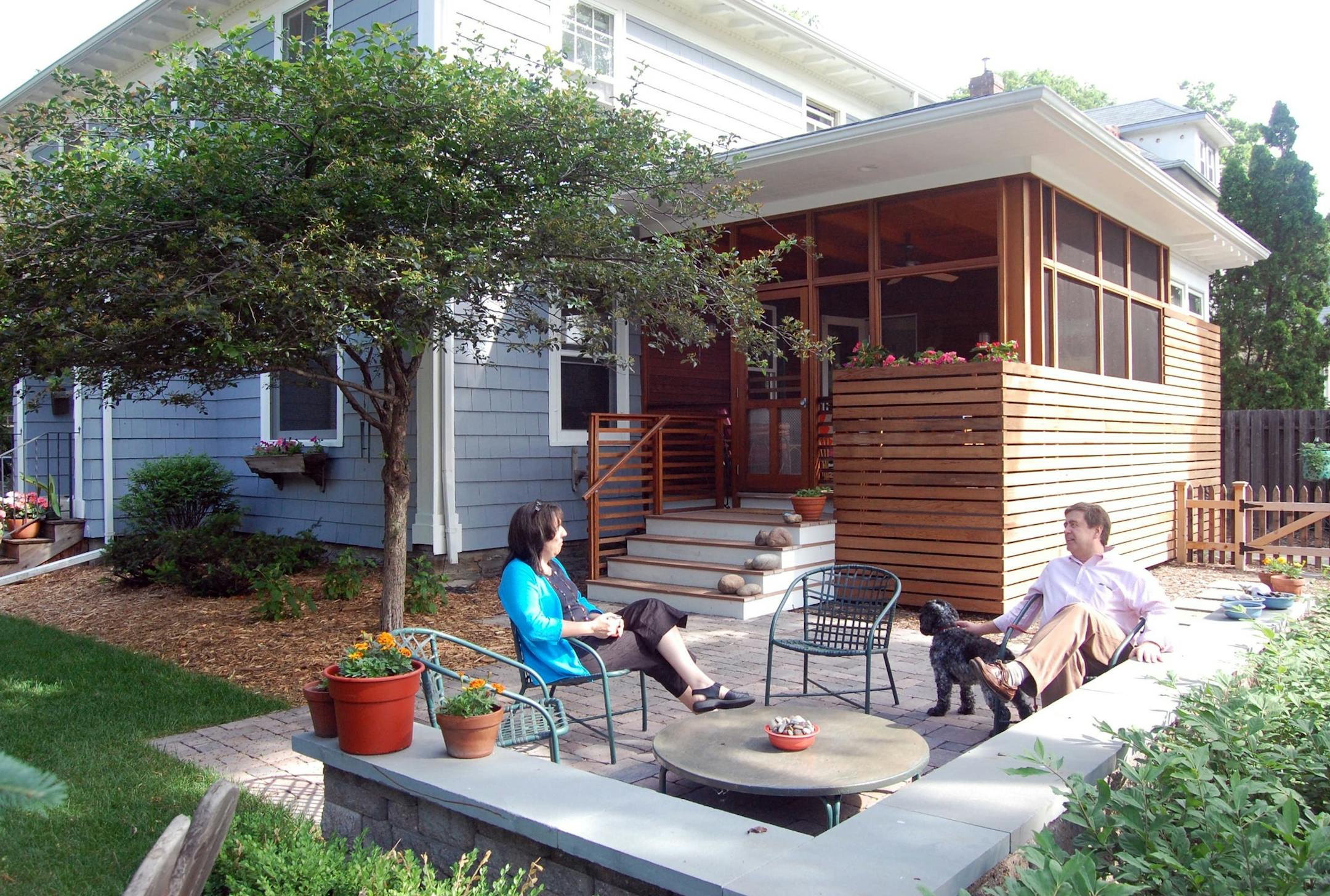 Bette Erickson and Paul Chrenka lounge on the new permeable paver patio, which is a few steps down from the screen porch and bathroom addition.