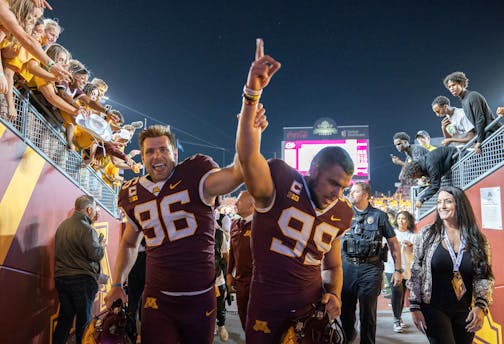 Gophers punter Mark Crawford and kicker Dragan Kesich exit the Huntington Bank field after defeating Nebraska 13-10 on Thursday