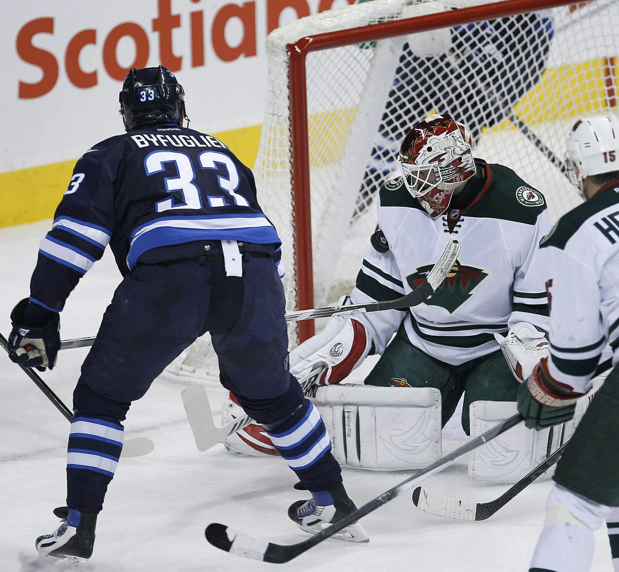Winnipeg Jets' Dustin Byfuglien (33) scores on Minnesota Wild's goaltender Niklas Backstrom (32) as Jets' Anthony Peluso (14) and Wild's Dany Heatley (15) and Nate Prosser (39) look on during first-period NHL hockey game action in Winnipeg, Manitoba, Friday, Dec. 27, 2013. (AP Photo/The Canadian Press, John Woods)