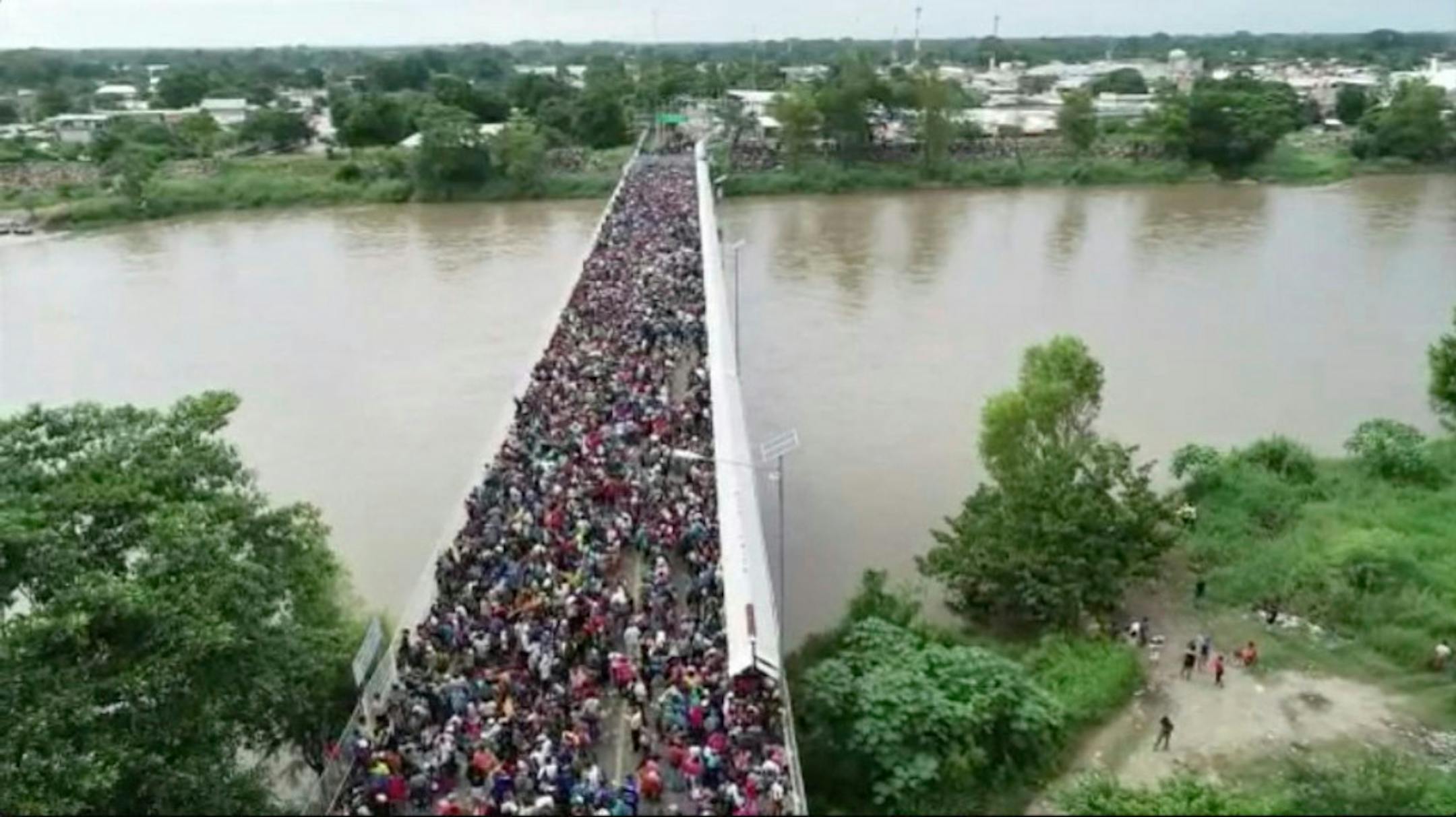 This Oct. 19, 2018 frame grab from video provided by Televisa, shows migrants bound for the U.S.-Mexico border waiting on a bridge that stretches over the Suchiate River, connecting Guatemala and Mexico, in Tecun Uman, Guatemala.