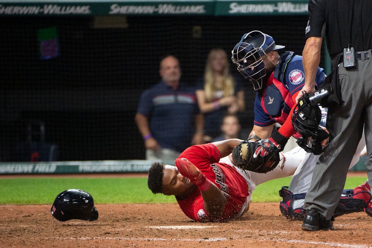 Minnesota Twins' Sandy Leon, second from left, tags out Cleveland Guardians' Oscar Gonzalez, left, at home plate during the 12th inning of the second 