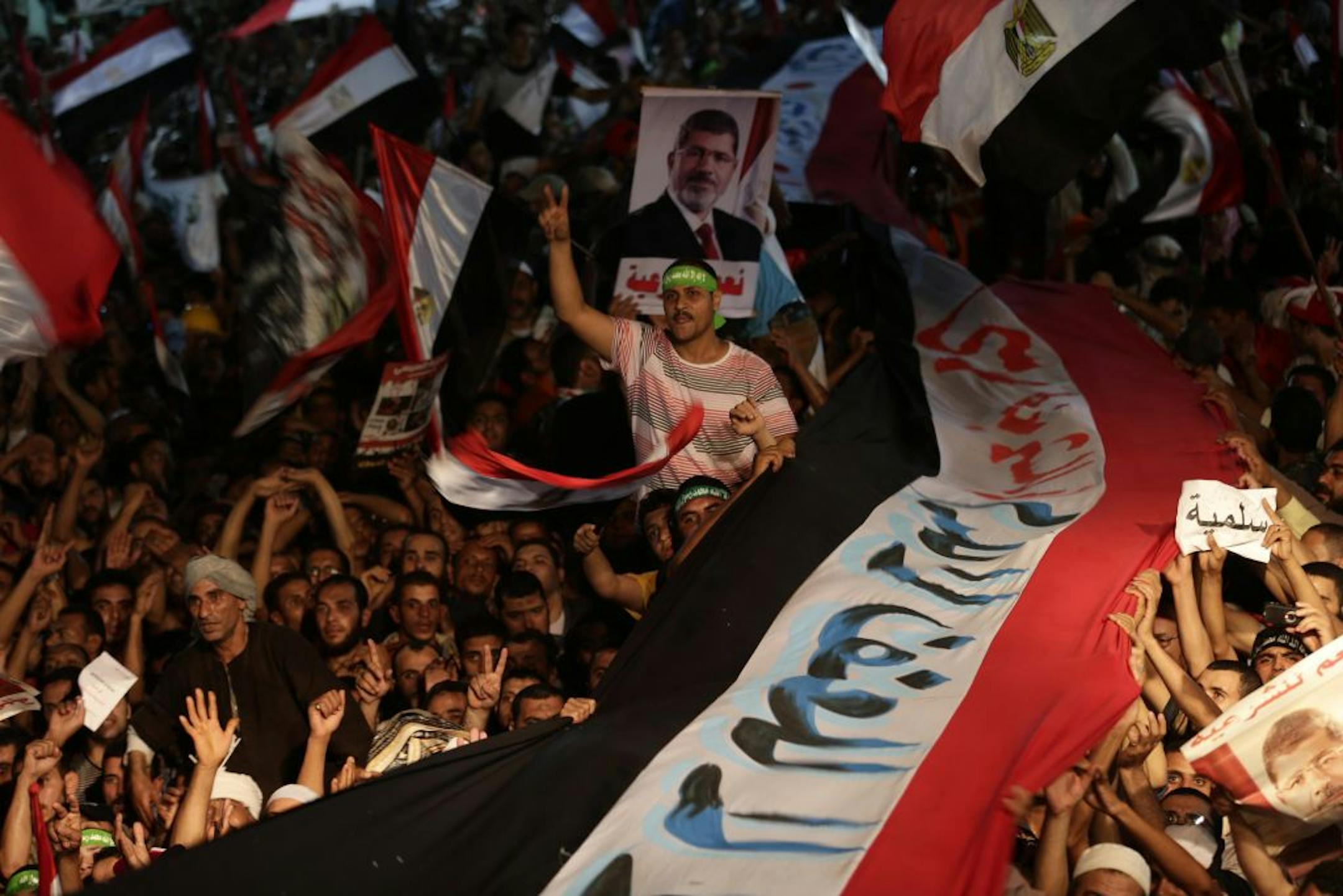 Supporters of Egypt's ousted President Mohammed Morsi hold a large Egyptian national flag as chant slogans against Egyptian Defense Minister Gen. Abdel-Fattah el-Sissi outside Rabaah al-Adawiya mosque, where supporters of Egypt's ousted President Mohammed Morsi have installed a camp and hold daily rallies at Nasr City, in Cairo, Egypt, Friday, Aug. 2, 2013. Authorities outlined plans Friday to break up two sit-ins by supporters of deposed President Mohammed Morsi, saying they would set up a cord