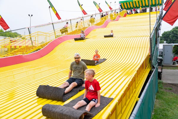 Fairgoers smile and laugh as they ride down The Giant Slide Thursday, Aug. 24, 2023, at The State Fairgrounds in Falcon Heights, Minn.