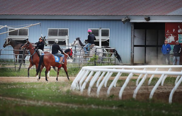 Exercise riders and horses head to and from the track at Canterbury Park in Shakopee.