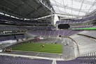 Workers lay down artificial turf at US Bank Stadium.