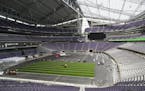 Workers lay down artificial turf at US Bank Stadium.