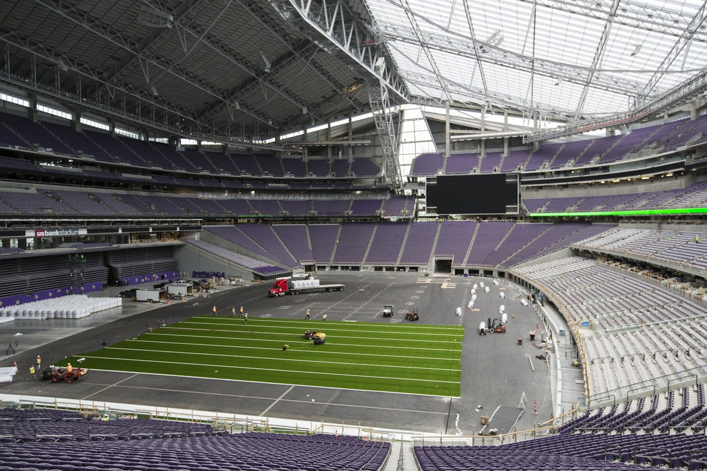 Workers lay down artificial turf at US Bank Stadium.