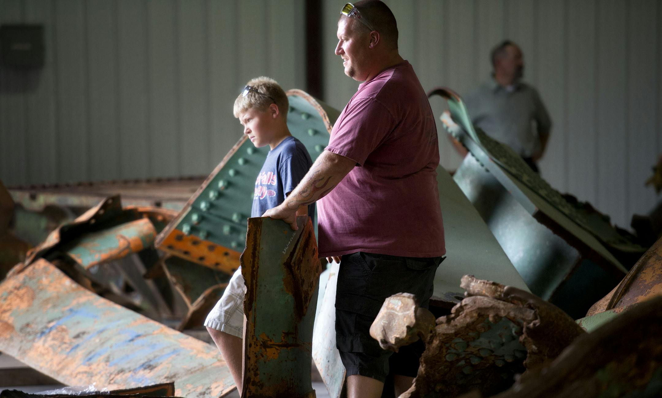 Dave Dahl, right, and his son David, who survived the I-35W bridge collapse with his mom and sister, waited for help to move a large piece of steel they were taking.