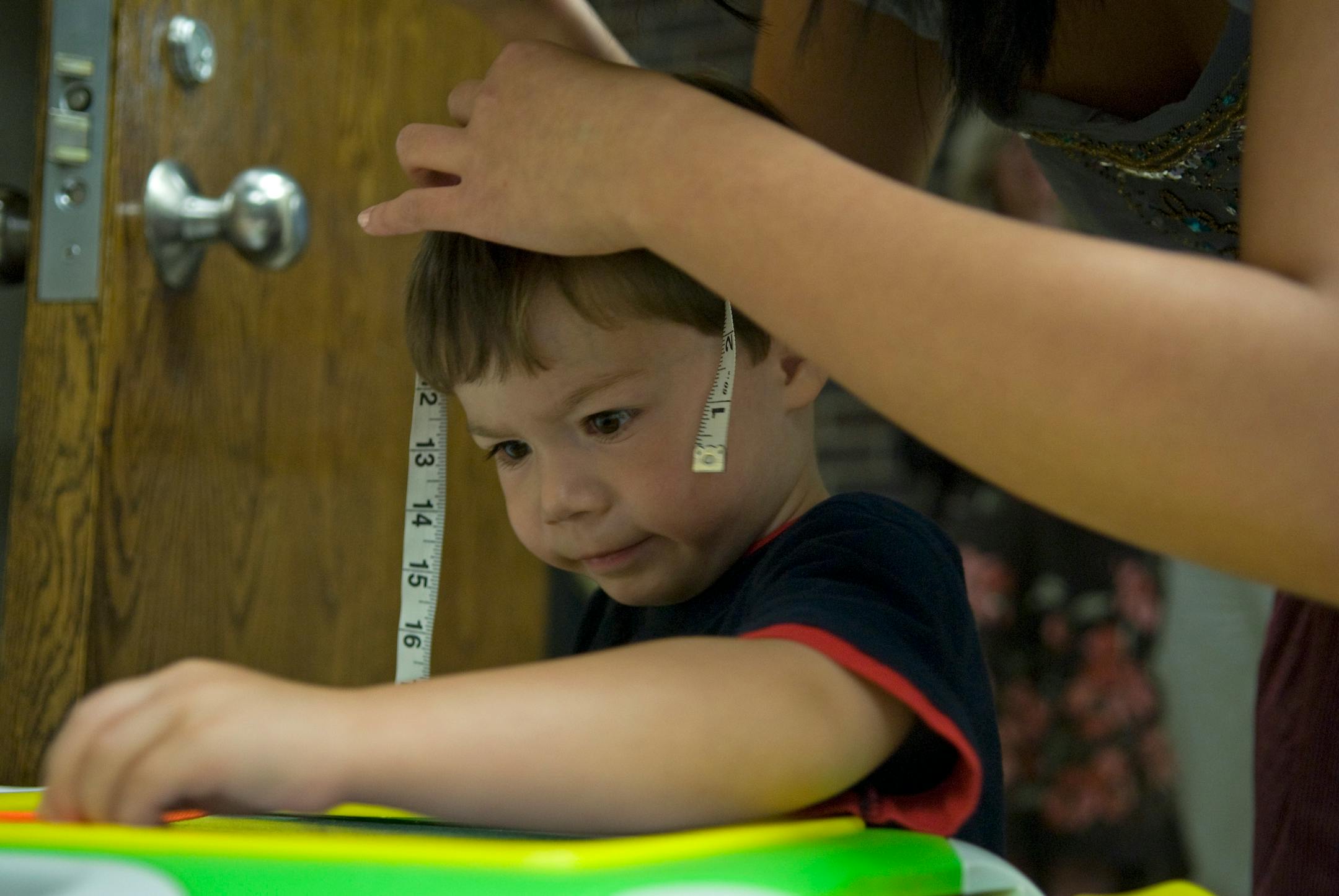 Lab assistant Celeste Tebedge takes a measurement of Aidan Oakman's head to determine where the center of his head is in order to place the EEG hat in the proper location.