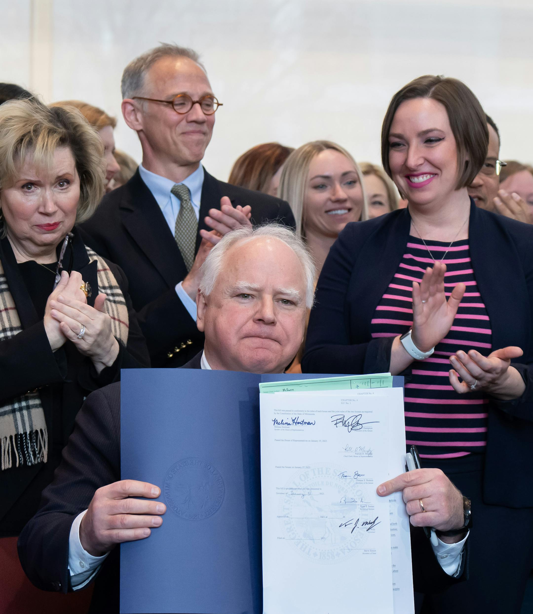 Surrounded by DFL legislators, Gov. Tim Walz signs a bill to add a "fundamental right" to abortion access into state law.