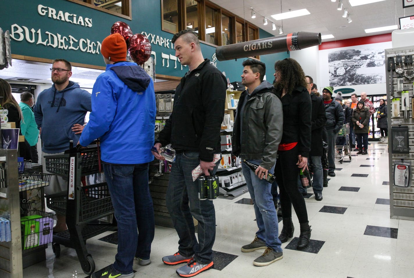 People wait in a long line for checking out inside of the Surdyk's liquor store on Sunday. March 12, 2017.