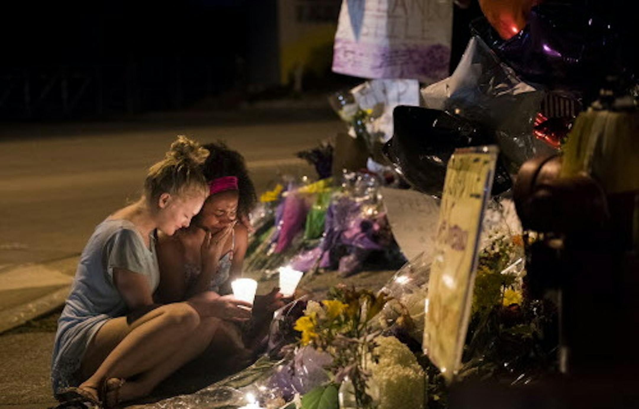 In this Friday, July 8, 2016 photo, Rue Norman, 19, right, cries as she prays with Olivia Gruver, 19, at a memorial on the roadside near where Philando Castile was killed in St. Paul, Minn. Castile was killed by St. Anthony Police Officer Jeronimo Yanez during a traffic stop. (Isaac Hale/Star Tribune via AP)