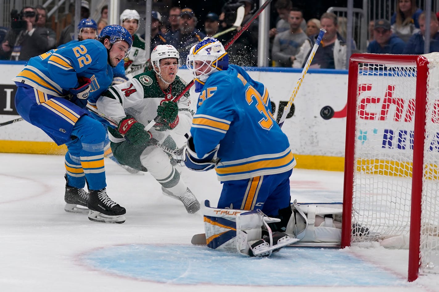 A shot by Minnesota Wild's Joel Eriksson Ek (14) sails past St. Louis Blues goaltender Ville Husso (35) as Blues' Logan Brown (22) watches during the first period of an NHL hockey game Saturday, April 16, 2022, in St. Louis. (AP Photo/Jeff Roberson)