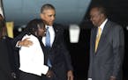 President Barack Obama embraces Auma Obama, his half-sister, as President Uhuru Kenyatta of Kenya looks on, at Jomo Kenyatta International Airport in 