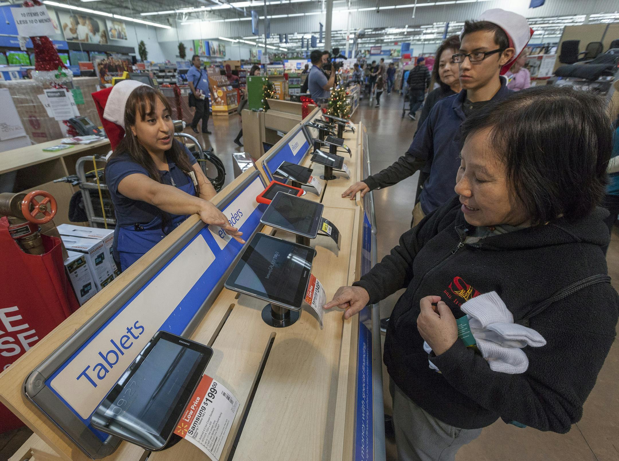 Walmart associate Danae Salcedo, left, assists consumers shopping for tablets at the Pre-Black Friday event at the Walmart Supercenter store in Rosemead, Calif., Wednesday, Nov. 21, 2012. (AP Photo/Damian Dovarganes) ORG XMIT: CADD105