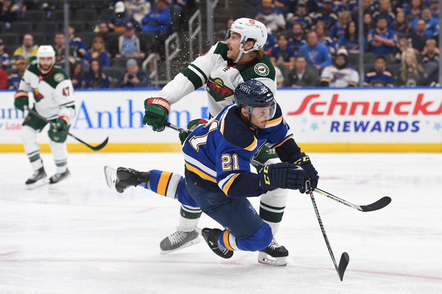 St. Louis Blues' Tyler Bozak (21) is checked by Minnesota Wild's Nicolas Deslauriers (44) during the second period in Game 4 of an NHL hockey Stanley Cup first-round playoff series on Sunday, May 8, 2022, in St. Louis. (AP Photo/Michael Thomas)