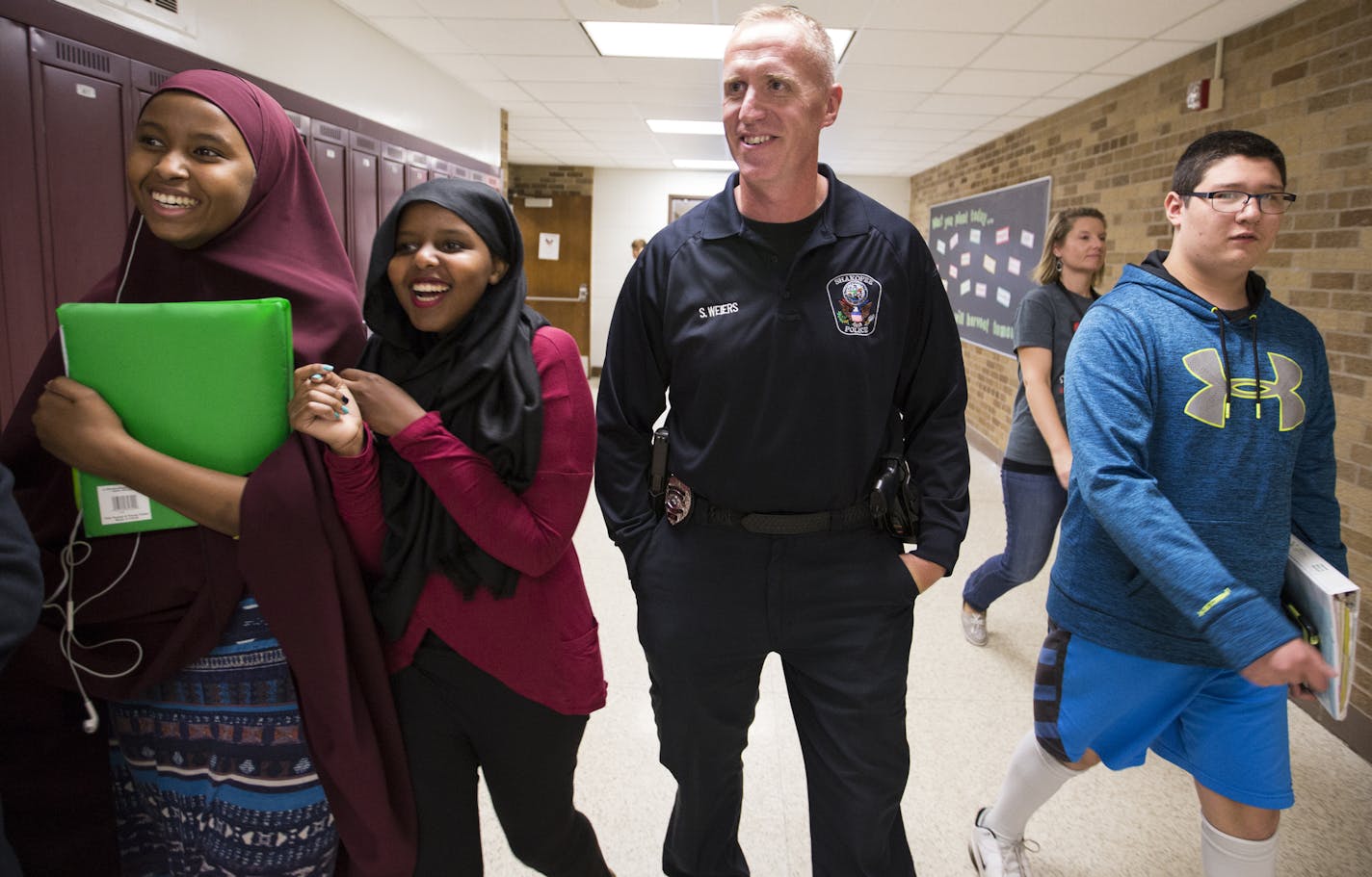 Shakopee Police officer Scott Weiers, center, chats with 8th grader Zuhur Hade, from left, 9th grader Aisha Guled and 8th grader Jazsper Krulikosky during passing period. ] (Leila Navidi/Star Tribune) leila.navidi@startribune.com BACKGROUND INFORMATION: Shakopee Police officer Scott Weiers patrols the hallway during the passing period at Shakopee West Junior High School on Tuesday, October 18, 2016.