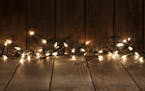 Empty rustic wooden table with defocused Christmas lights at background. Ideal for product display. Predominant colors are brown and yellow. DSRL stud