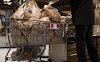 A shopper loads up a cart full of plastic bags at a grocery store in November.