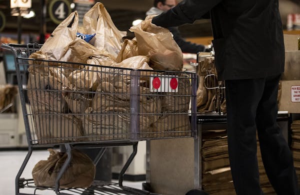 A shopper loads up a cart full of plastic bags at a grocery store in November.
