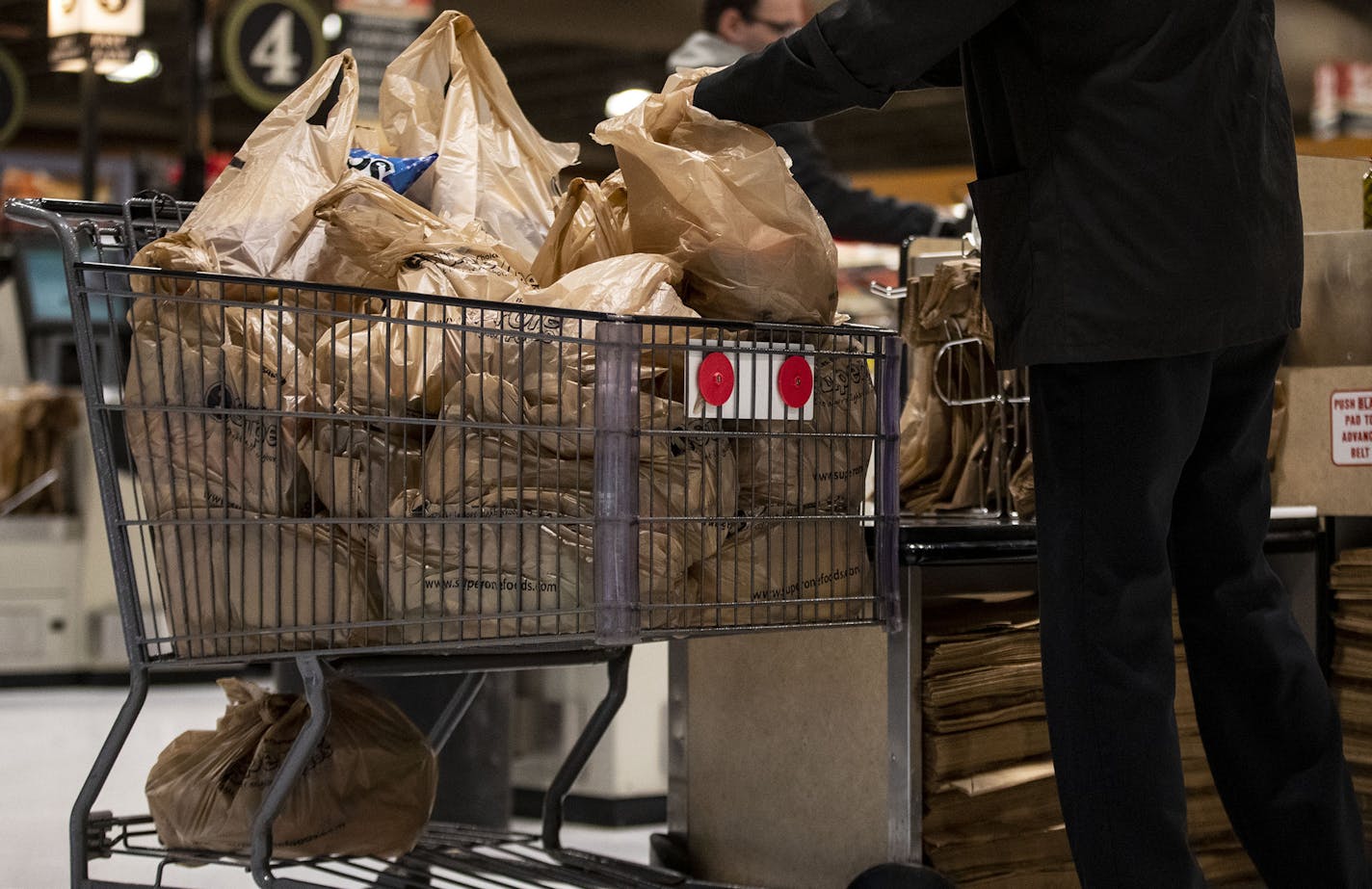 A shopper loads up a cart full of plastic bags at a grocery store in November.