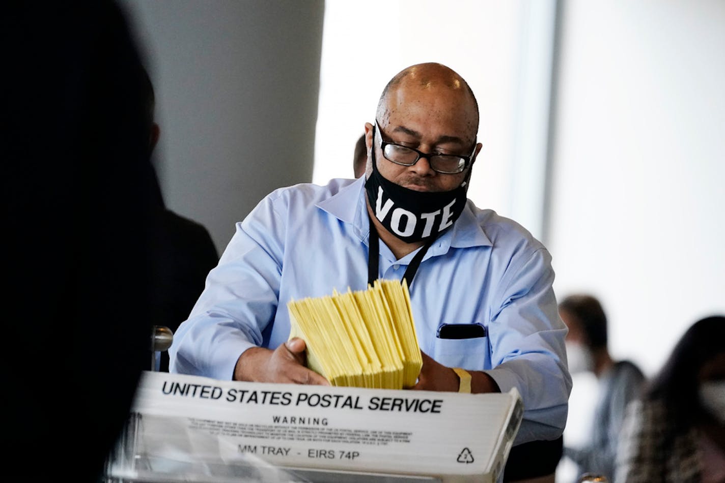 A election worker hands out ballots to be counted at State Farm Arena on Thursday, Nov. 5, 2020, in Atlanta. (AP Photo/Brynn Anderson)