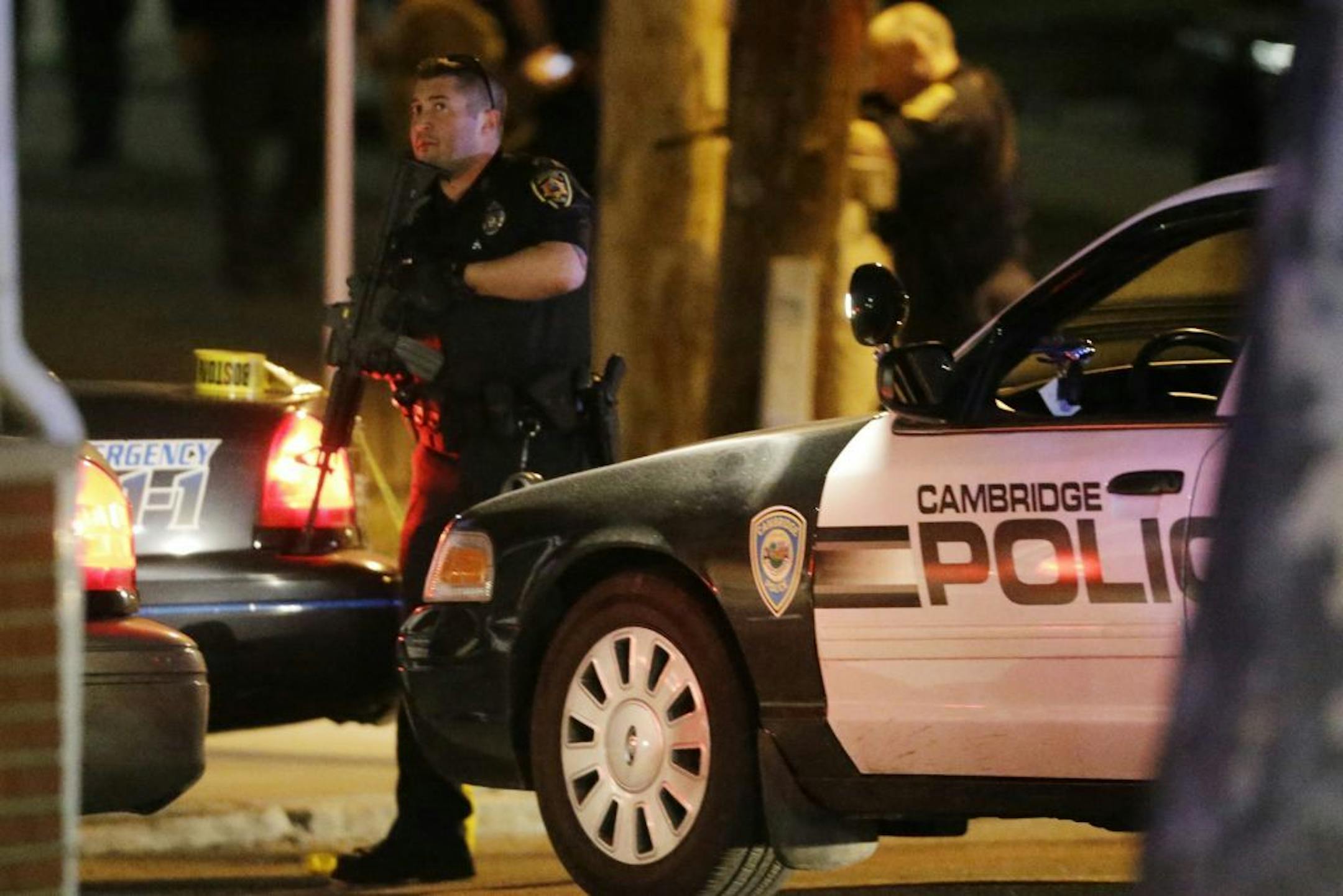 Police officers stand ready at a crime scene Friday, April 19, 2013, in Watertown, Mass. A tense night of police activity that left a university officer dead on campus just days after the Boston Marathon bombings and amid a hunt for two suspects caused officers to converge on a neighborhood outside Boston, where residents heard gunfire and explosions.