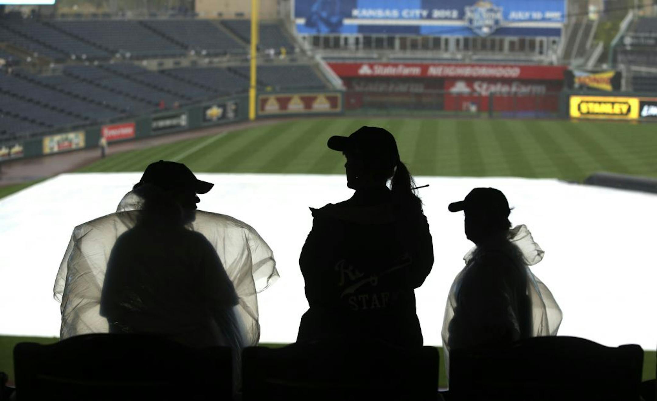 Kauffman Stadium ushers take cover as they watch rain fall before a baseball game between the Minnesota Twins and Kansas City Royals Friday, Aug. 31, 2012, in Kansas City, Mo. The game was canceled due to rain and a doubleheader will be played on Saturday.