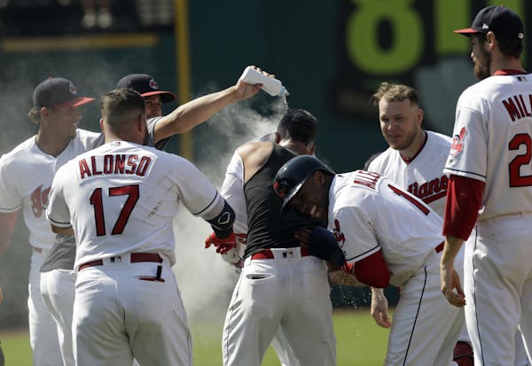 Cleveland Indians teammates mob Michael Brantley after he hit the game-winning RBI-single in the ninth inning of a baseball game against the Minnesota