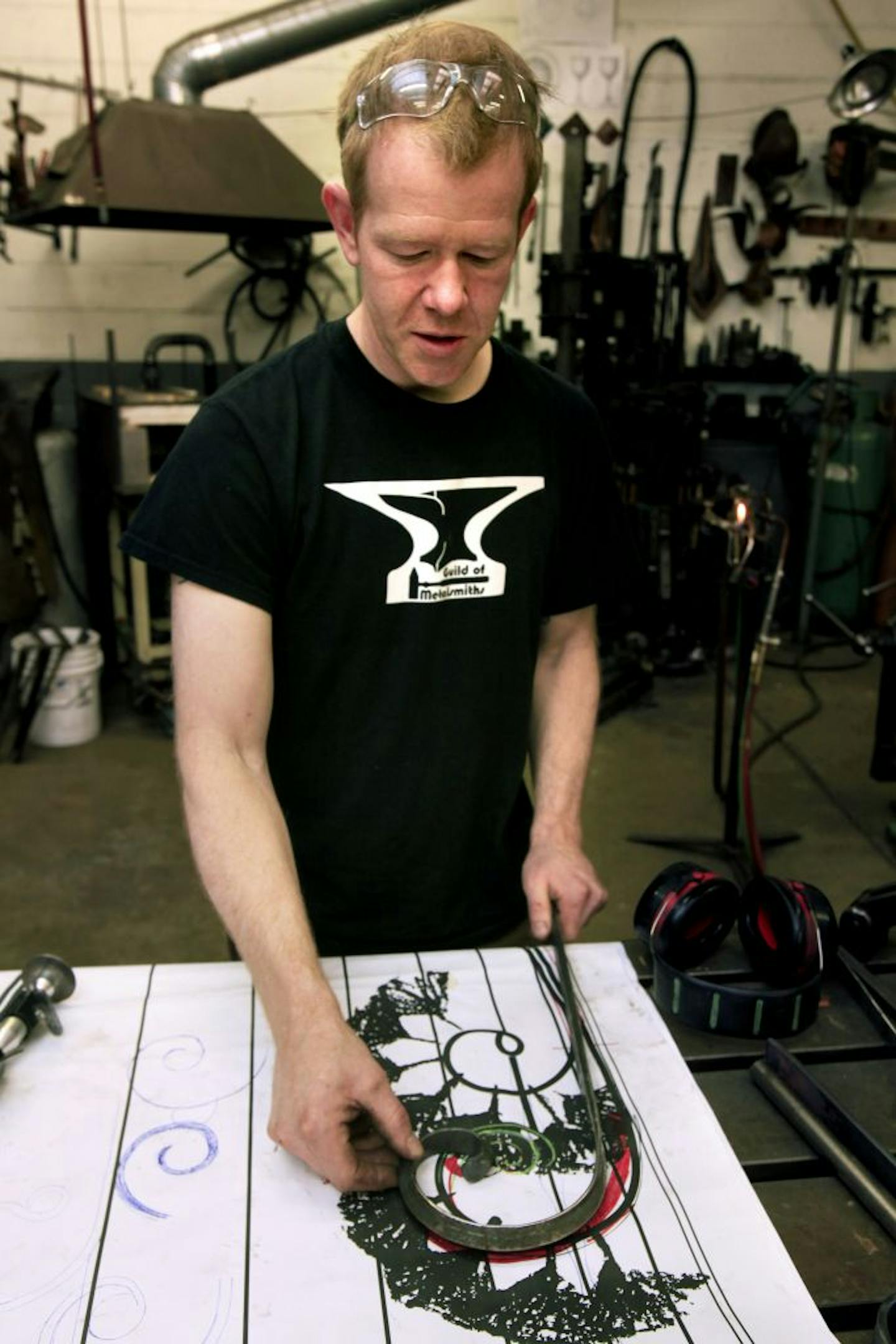 Metalsmith, Chris Rand, creates custom architectural metalwork for clients. Chris checks the metal against a full size patern he created for the project to make sure the pieces will fit the desired pattern. May 22, 2012.